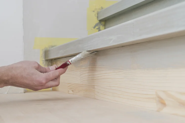 Lackieren einer Holzleiste mit dem Pinsel